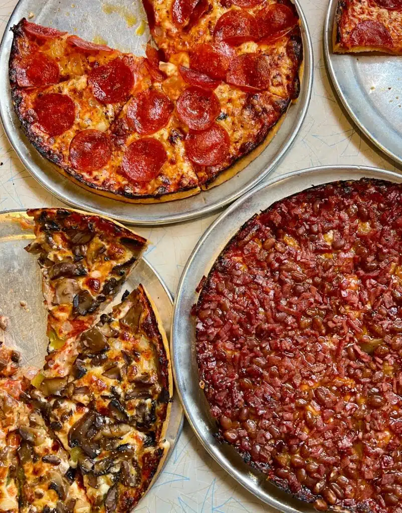A trio of South Shore bar pizza pies from Lynwood. The Bean Special comes topped with Boston baked beans, onion, and salami.